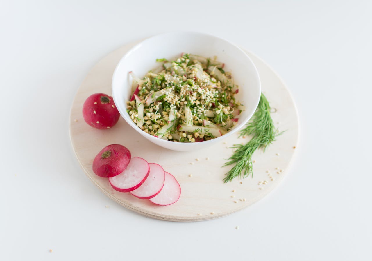A healthy vegan salad with buckwheat, radish, and dill garnished with sesame seeds.